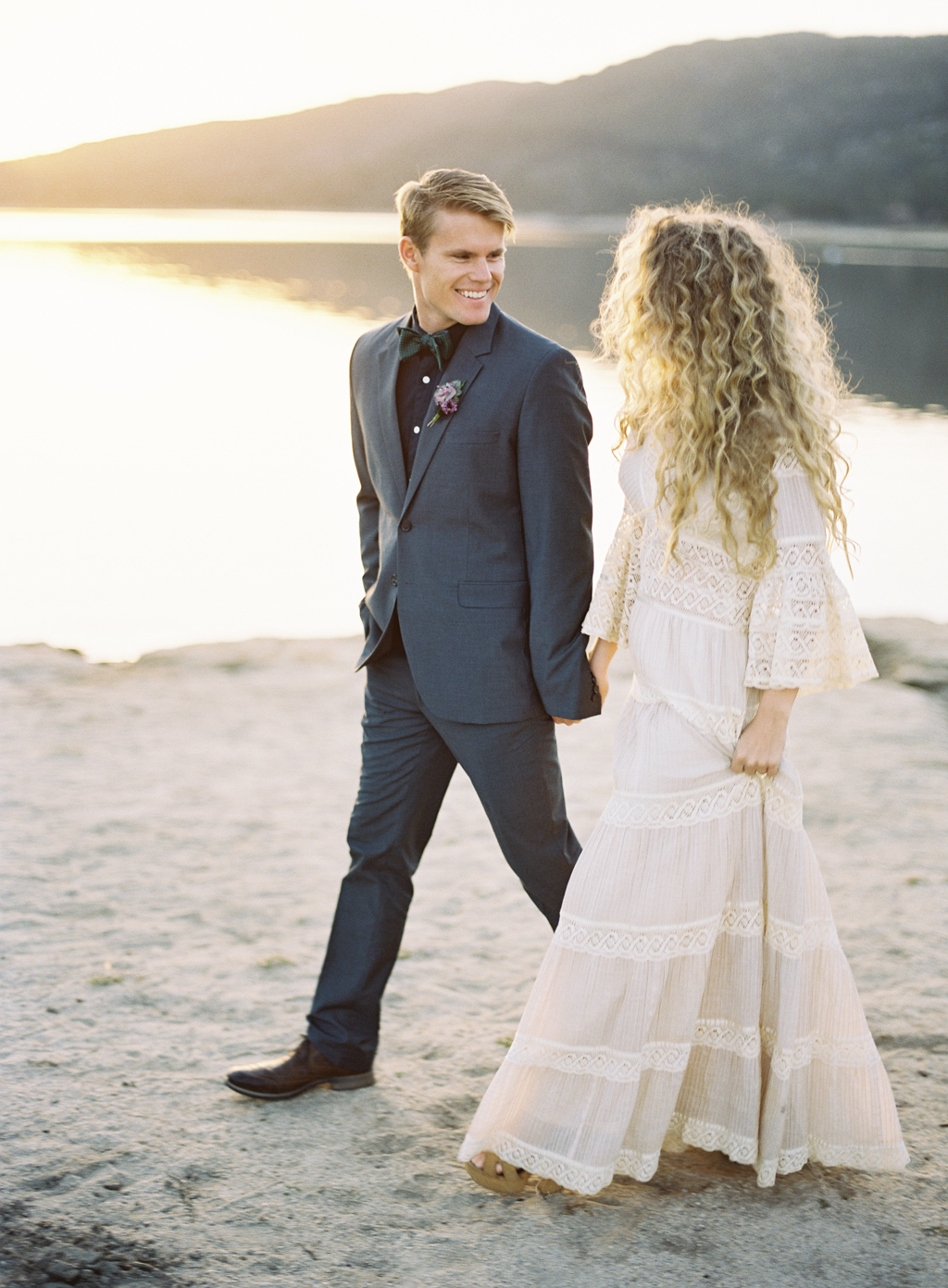 a film photogaph of bride and groom walking lakeside in california