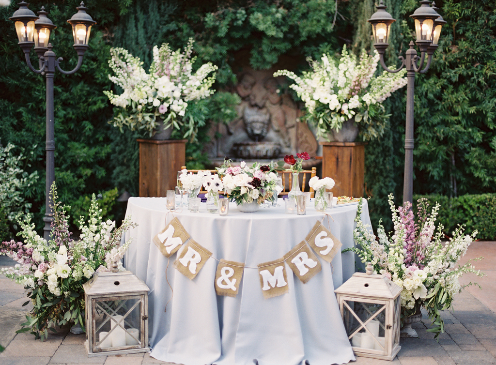 a sweetheart table surrounded by floral arrangement by art with nature and with a sign that says mr. and mrs. in orange county