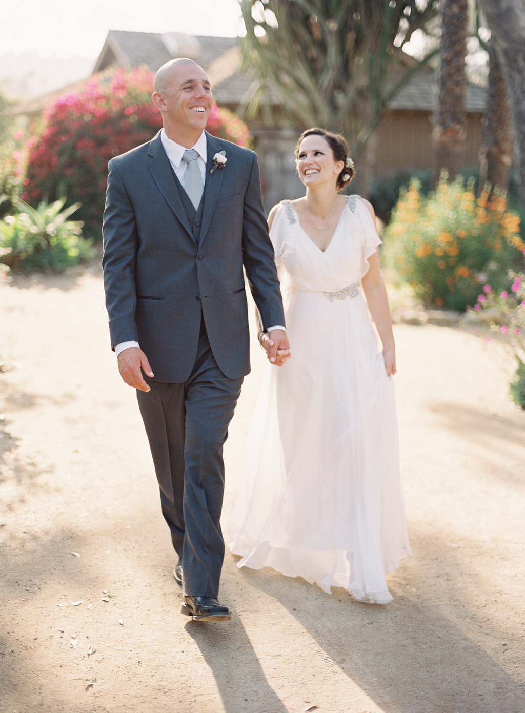 a film photograph of a bride and groom walking through a park full of succulents and cacti in orange county