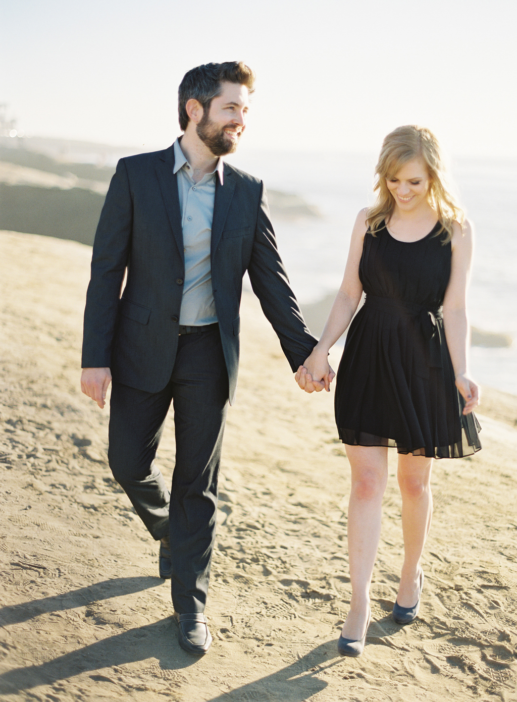 an engaged couple walkes along the coast for their engagement session in southern california with a film photographer.