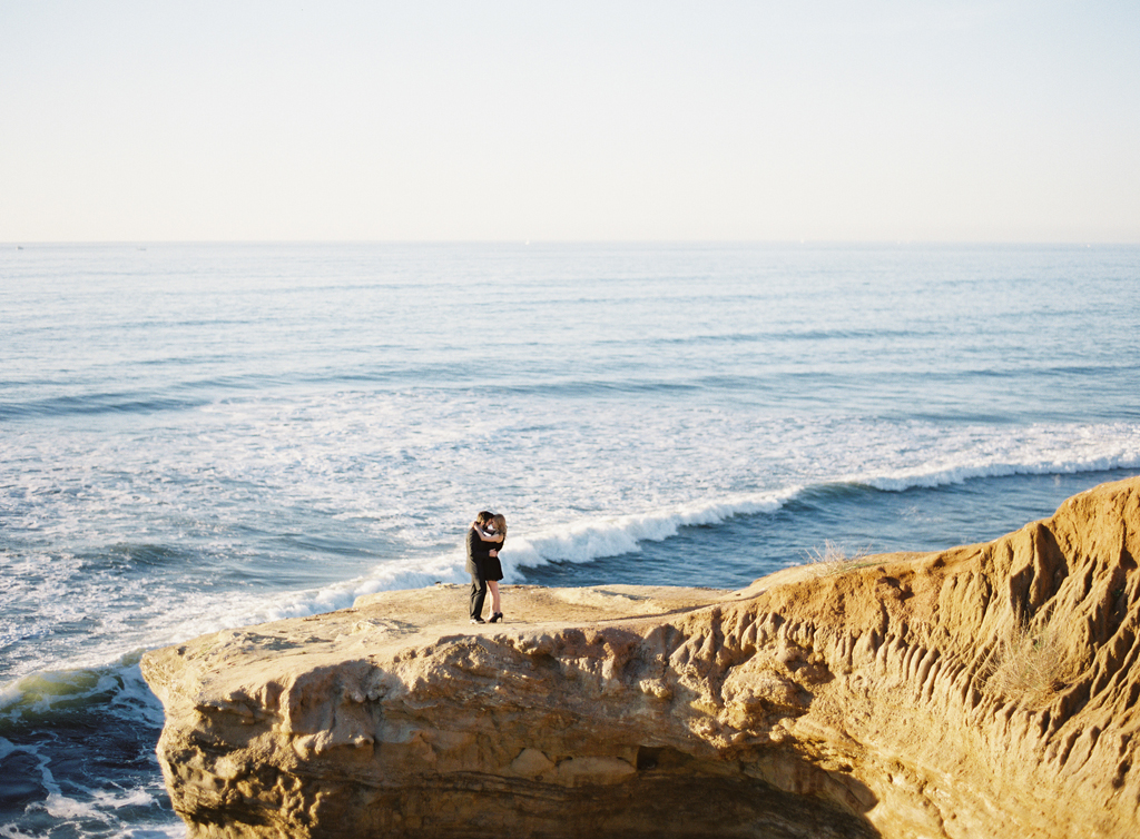 an engaged couple stands on a cliff along the coast for their engagement session.  captured on fuji 400h film and a mamiya 645 camera.
