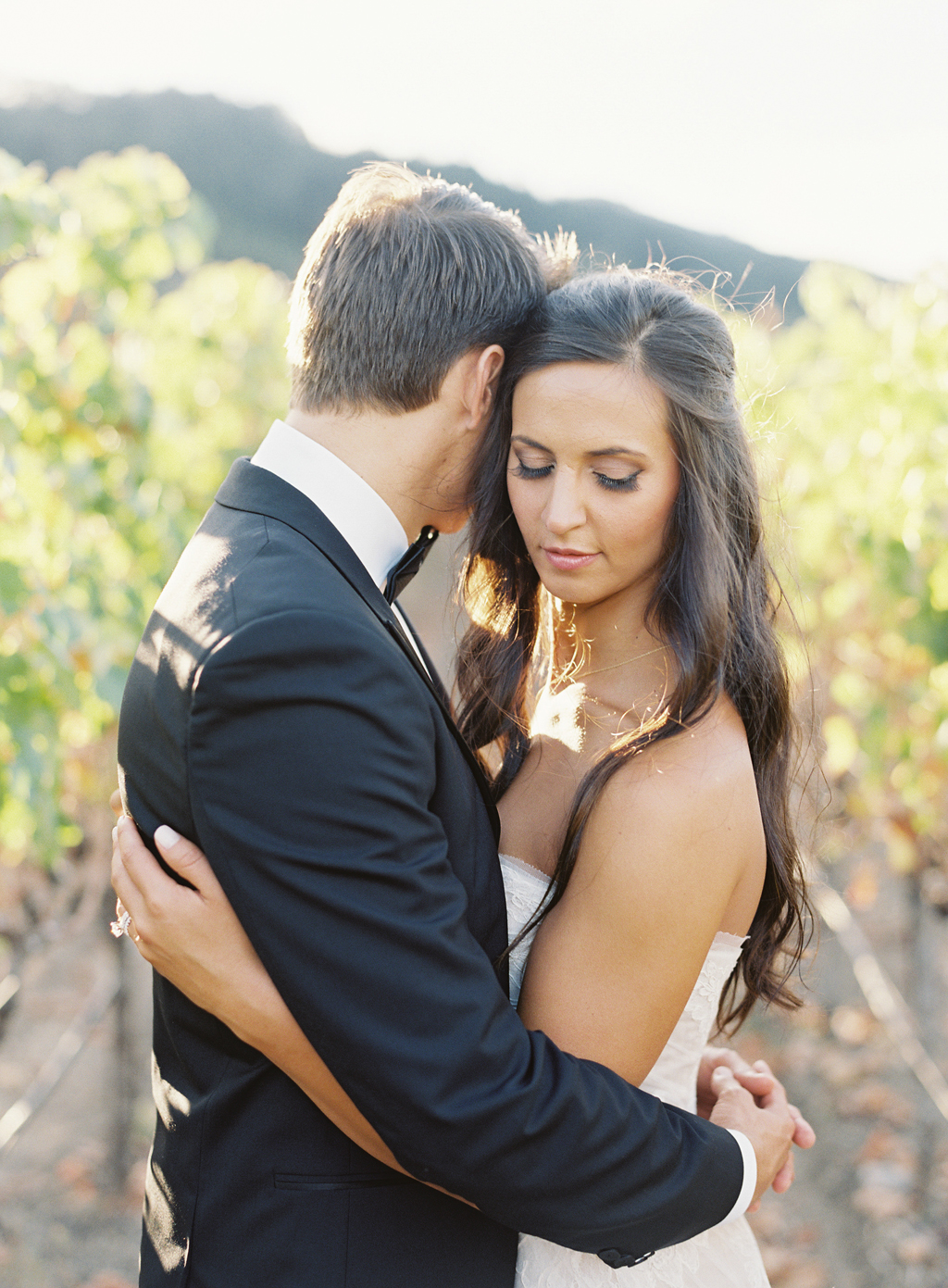 A couple embrace for a portrait in a napa vineyard shot on film photography.