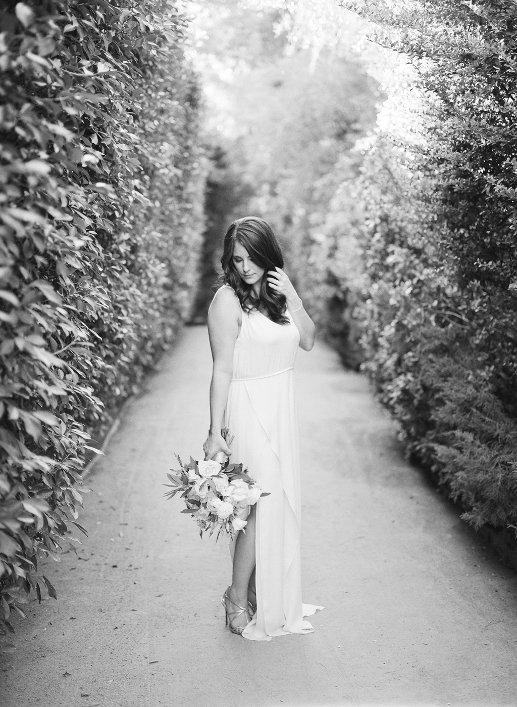a photo of a bride posing in the pathways at the parker palm springs shot on black and white film.