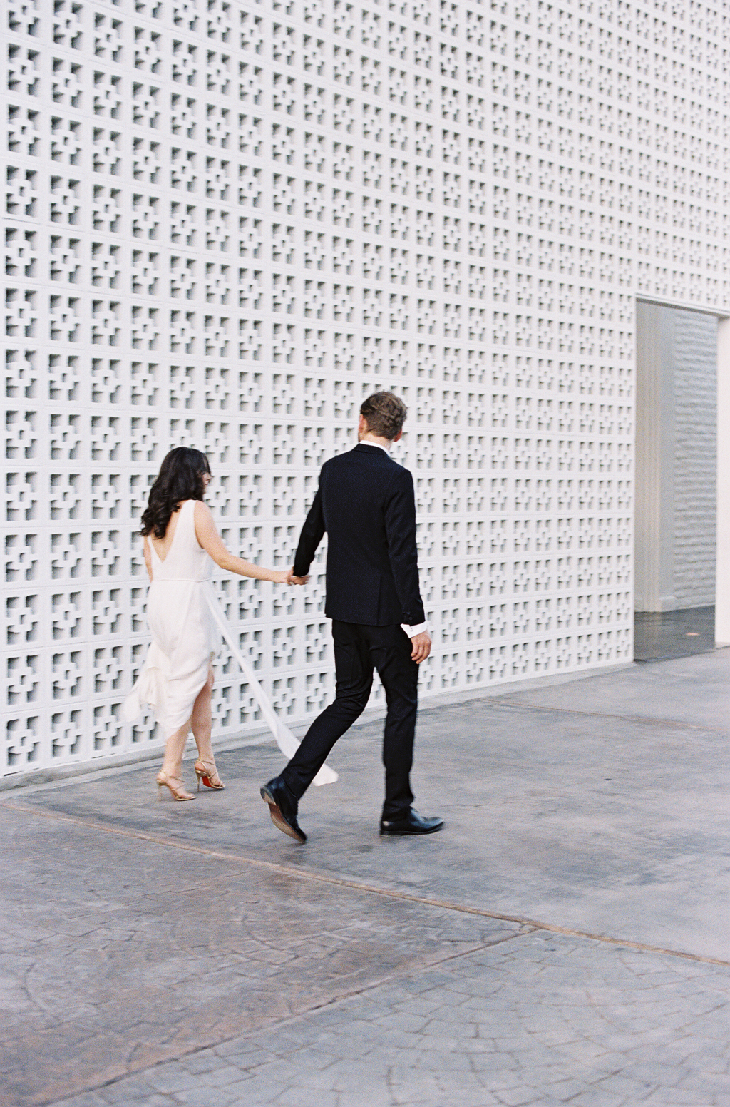 a newly married couple walk near the entrance of the parker palm springs hotel in California.