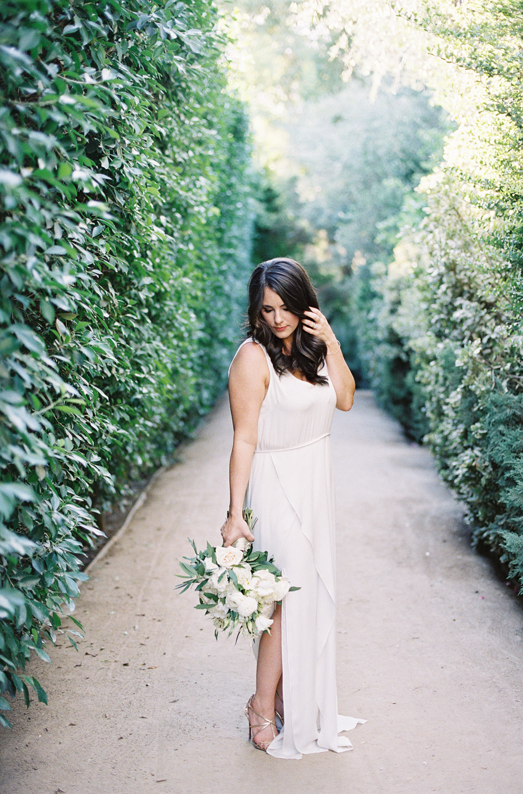 a bride poses for a film photograph in the pathways at the parker hotel palm springs.