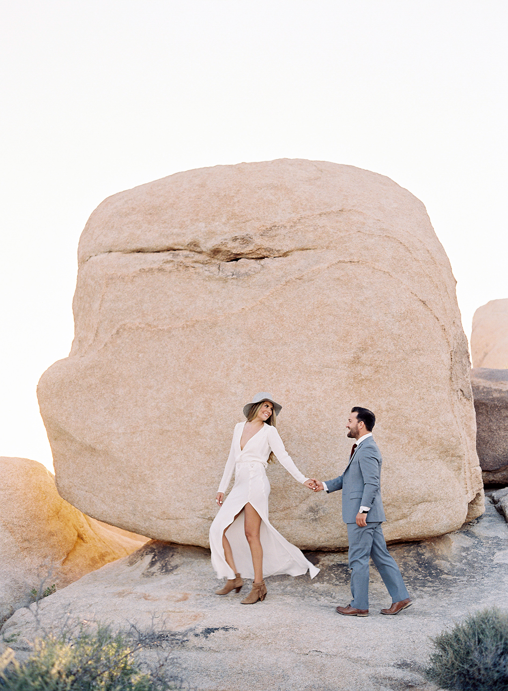 An engaged couple walking through Joshua Tree National Park for their engagement session.